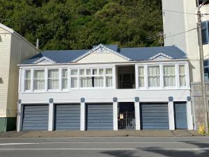 a white house with two garage doors on a street at Beach house in Oriental Parade in Wellington