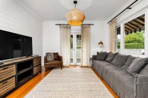 a living room with a couch and a flat screen tv at Quarry Hill Cottage, 1 minute walk into Berrima. in Berrima