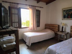 a bedroom with two beds and a tv and a window at Hostería La María in Rosario de la Frontera