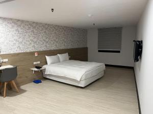 um quarto com uma cama branca e uma televisão em Tie Dao Hotel em Tainan