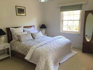 a bedroom with a bed with a white comforter and a window at York Cottage. A Country Retreat in Burradoo. in Burradoo