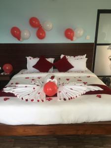 Una cama con almohadas rojas y blancas y globos. en The North Face Inn, en Pokhara