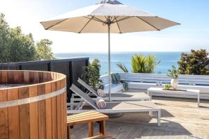 a patio with an umbrella and a table and chairs at Ocean Breeze Cottage - Coast & Country in Onetangi
