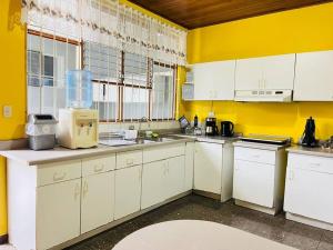 a kitchen with white cabinets and yellow walls at Alojamiento Tiquicia Valley in Alajuela City