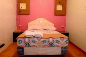 - un petit lit dans une chambre avec un mur rose dans l'établissement MOJOKERTO GUESTHOUSE, à Mojokerto