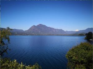 una gran masa de agua con montañas al fondo en Cabaa Oregn con hot tub exclusivo cerca de termas y lago, en Coñaripe