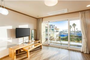 ein Wohnzimmer mit einem TV und einem großen Fenster in der Unterkunft Dombe Resort in Seogwipo