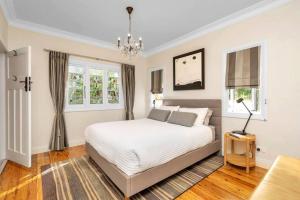 ein weißes Schlafzimmer mit einem Bett und einem Kronleuchter in der Unterkunft Willow Tree Cottage in Bustling Creative Bundanoon in Bundanoon