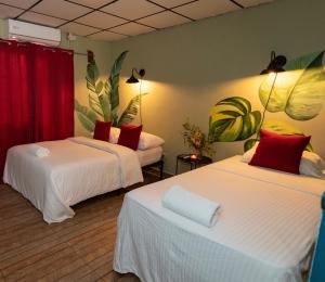 2 Betten in einem Zimmer mit roten Vorhängen und Pflanzen in der Unterkunft Hostel Travelers Santiago in Santiago