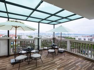 eine Terrasse mit Tischen, Stühlen und Sonnenschirmen auf einem Balkon in der Unterkunft Ha Long Essence Classic Hotel in Hạ Long