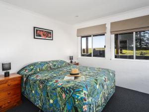 a bedroom with a bed with a hat on it at Aqua Vista - Beach front location in Brooms Head