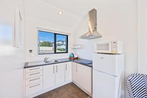 a white kitchen with a sink and a microwave at STUDIO ON KINGS in Wanaka