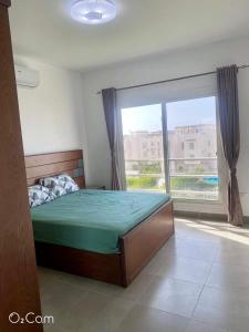 - une chambre avec un lit et une grande fenêtre dans l'établissement Sidi Abd El-Rahman Amwaj duplex HUGE garden pool., à El Alamein