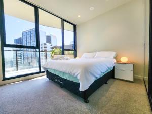 a bedroom with a large bed and large windows at Modern 2-bedrooms apartment with parking in Melbourne