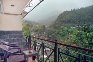 a balcony with chairs and a view of a mountain at Nandini villa in Dharmsāla