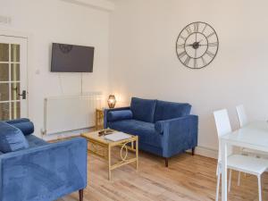 una sala de estar con sofás azules y un reloj en la pared en The Secret Garden, en Ayr