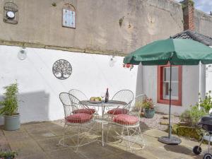 een tafel met stoelen en een parasol op een patio bij The Secret Garden in Ayr