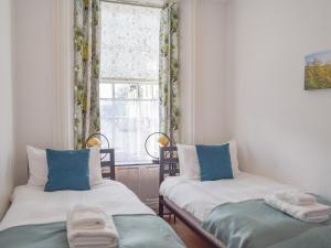 two beds in a small room with a window at The Secret Garden in Ayr