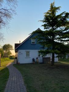 ein weißes Haus mit einem Baum und einer steinernen Einfahrt in der Unterkunft Freistehendes Einfamilienhaus mit Boddenblick Nähe Ostsee in Fuhlendorf