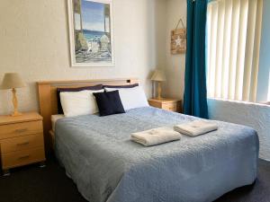 1 dormitorio con 1 cama con 2 toallas en Ocean Drive Apartments, en Merimbula