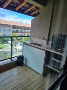 cocina con encimera con fregadero y ventana en La Fleur Polinesia Residence & Resort, en Porto de Galinhas