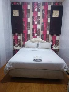a bedroom with a large white bed with clocks on the wall at MOJOKERTO GUESTHOUSE in Mojokerto