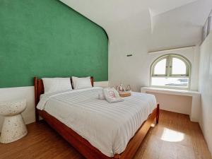 ein Schlafzimmer mit einem Bett mit einer grünen Wand in der Unterkunft Renjana Beach House in Bira