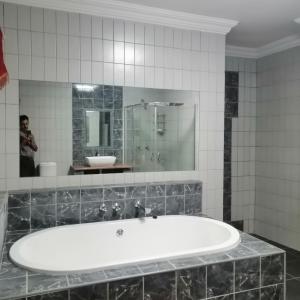 a man taking a picture of a bath tub in a bathroom at Villa Pretoria in Pretoria