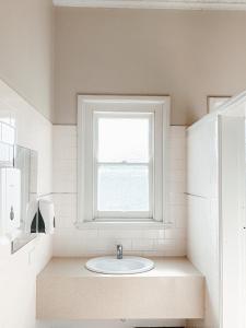 baño blanco con lavabo y ventana en Central Hotel Stroud, en Stroud