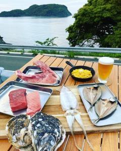 einem Holztisch mit Teller mit Speisen und einem Glas Bier in der Unterkunft 一棟貸し別荘つる in Matsue