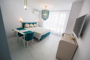 a white bedroom with a bed and a table and chairs at Pearl in Ravda