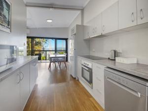a kitchen with white cabinets and a table in the background at Beachside Palms Unit 2 in Nelly Bay