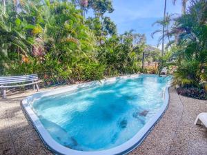una gran piscina con un banco y árboles en Beachside Palms Unit 2 en Nelly Bay