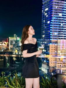 Una donna con un vestito nero in piedi sulla cima di una città di Odin Hotel Quy Nhon a Quy Nhon
