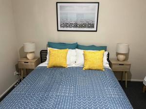 a bedroom with a bed with blue and yellow pillows at Caboolture South 3-bedroom Home in Caboolture