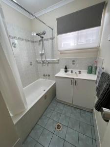 Caboolture South 3-bedroom Home في كابولتشر: حمام أبيض مع حوض ومغسلة