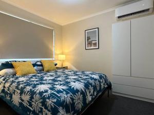 Caboolture South 3-bedroom Home في كابولتشر: غرفة نوم بسرير ازرق وبيض مع مخدات صفراء