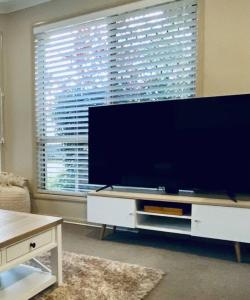 Caboolture South 3-bedroom Home في كابولتشر: غرفة معيشة مع تلفزيون بشاشة مسطحة كبيرة