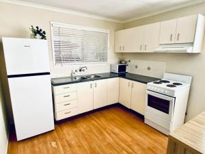 Caboolture South 3-bedroom Home في كابولتشر: مطبخ بأدوات بيضاء وأرضية خشبية