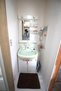 una persona que toma una foto de un baño con lavabo en 海と湖が近い一軒家　”民泊あばしりの家” 