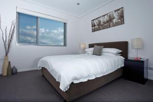 a white bedroom with a large bed and a window at Glebe Park Canberra City ACT in Canberra