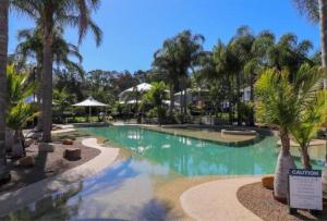 a pool at a resort with palm trees at Blue Lago at Raffertys Resort in Cams Wharf