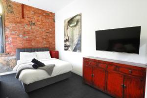 een slaapkamer met een bed met een tv en een bakstenen muur bij Bayside House in Melbourne