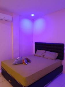 a room with a bed with purple lights on it at Satu Hati Homestay in Ekas