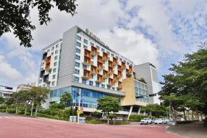 un gran edificio en una calle de la ciudad con coches aparcados en Bareve Hotel en Seogwipo