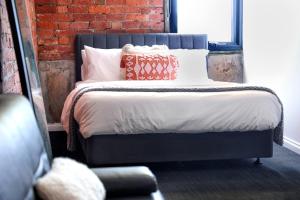 a bedroom with a bed with pillows and a brick wall at Bayside House in Melbourne