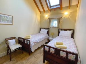 two beds in a room with two chairs and a window at The Beaches in Stalham
