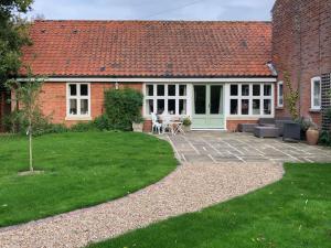 a brick house with a patio and a yard at The Beaches in Stalham