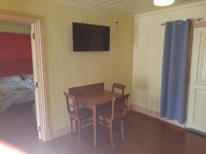Un comedor con mesa y sillas y un televisor. en Drovers Retreat, en Thulimbah