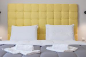 1 cama con cabecero amarillo y 2 almohadas blancas en City Life Athens Apartments, en Atenas